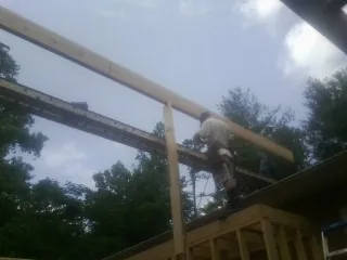 Carpenter setting a ridge beam over a new addition frame — Ice Dam Removal by Roofing Brothers in Mooreville