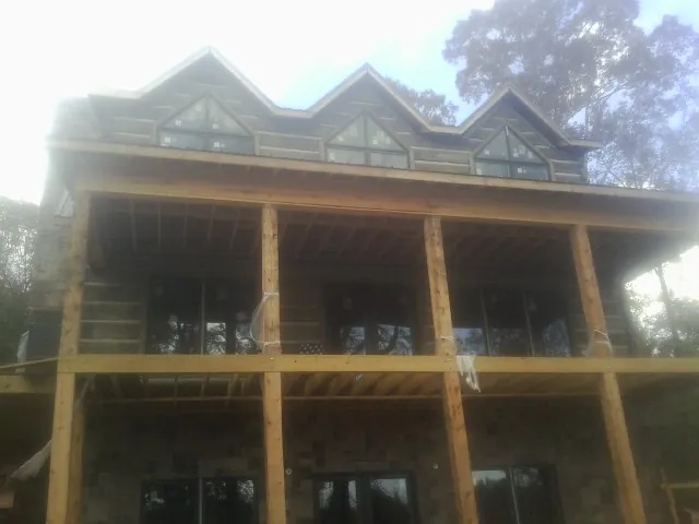 Dormers and porch framing on a large log home under construction — Roof Coating work by our crew in Mooreville