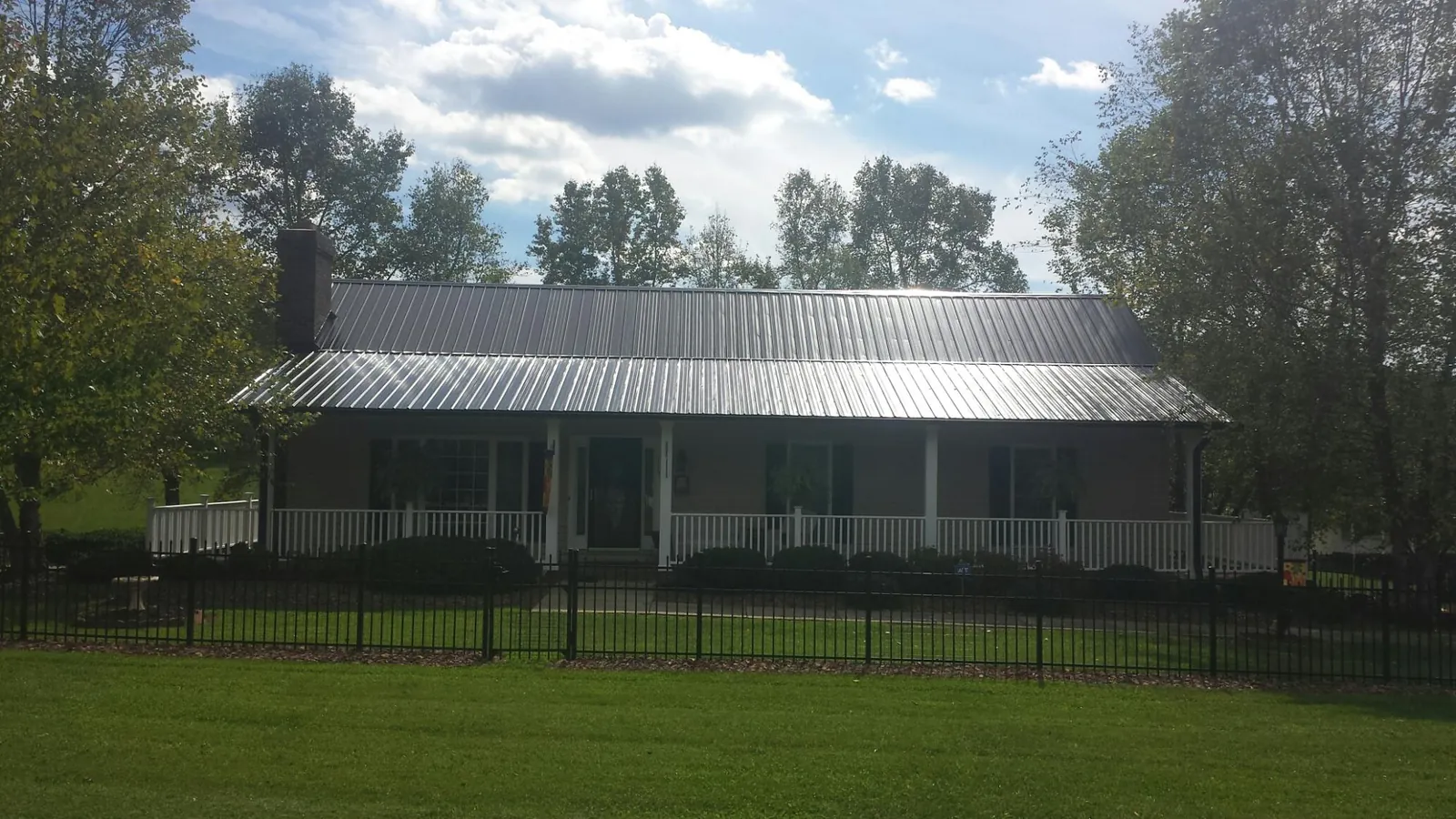 Gray metal roof on a brick ranch with a full width front porch — Gutter Guard Installation work by our crew in Mooreville