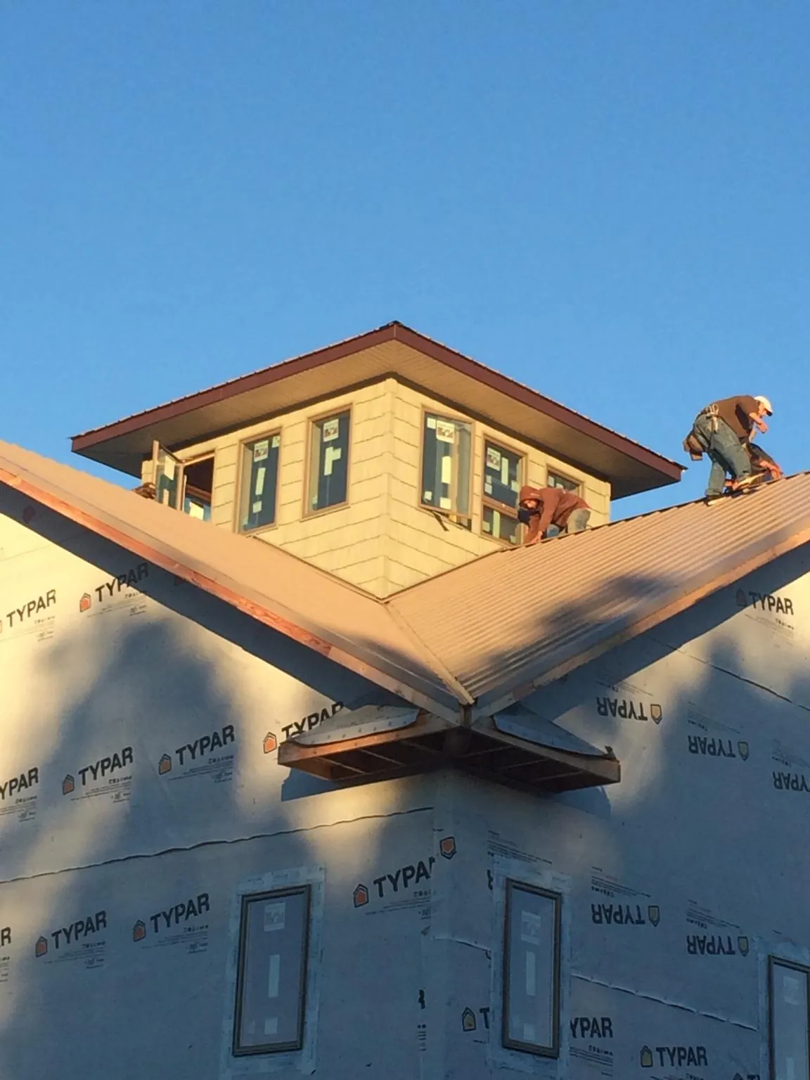 Roofers working around a rooftop cupola on a new metal roof at sunset — Roof Waterproofing in Mooreville by Roofing Brothers